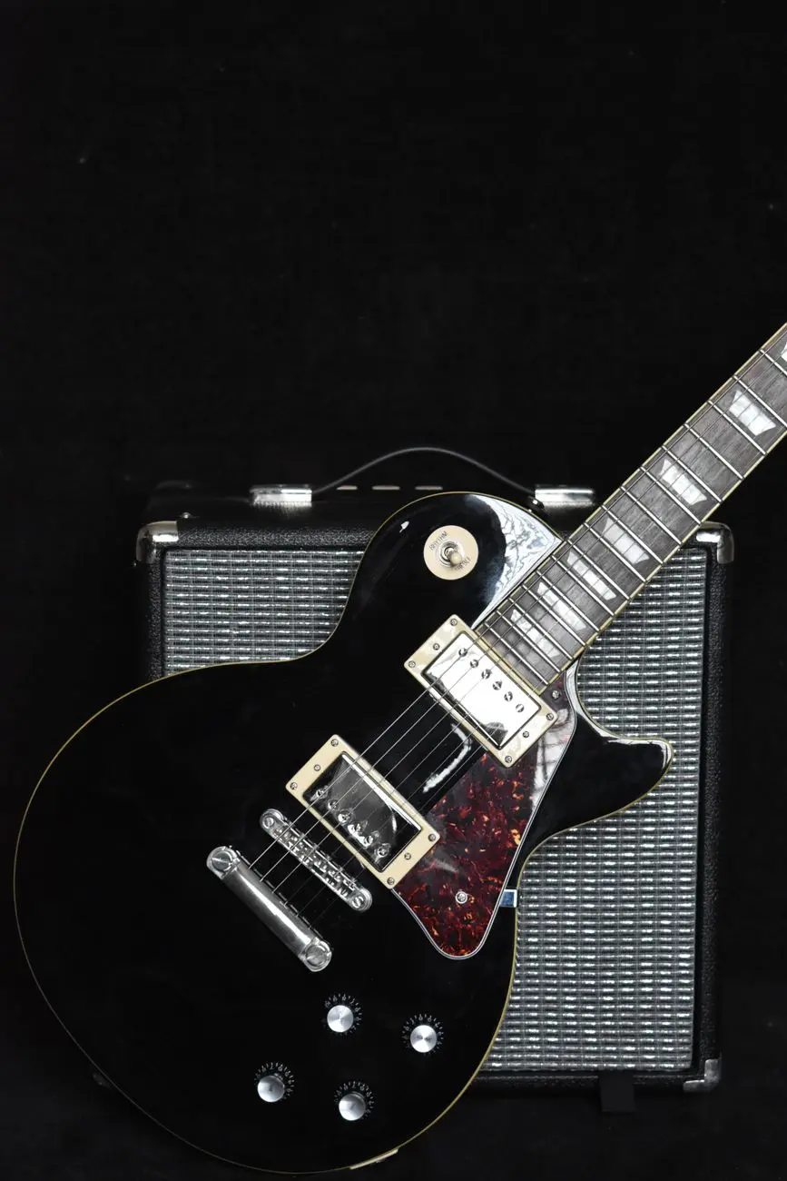 pexels photo 36288922 black electric guitar with amplifier on dark background